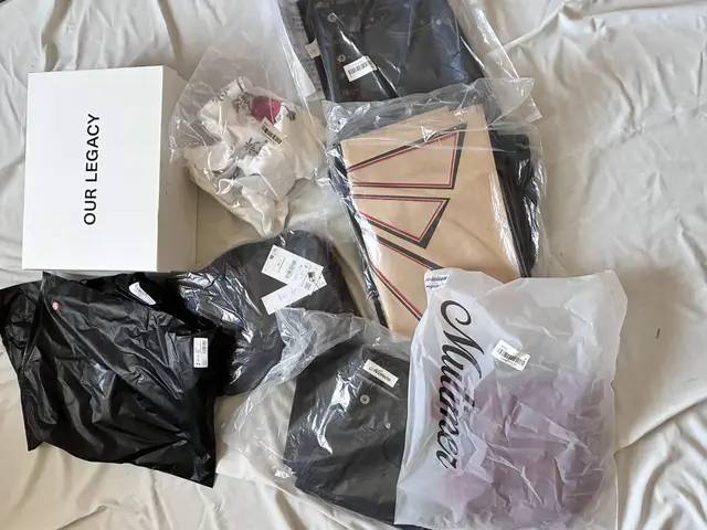 Our Legacy shoe box and packaged clothing laid out on a bed in the original 8kg Reddit haul photo
