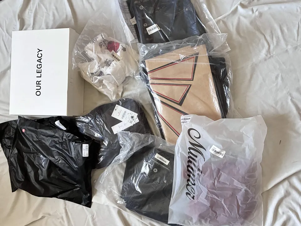 Our Legacy shoe box and packaged clothing laid out on a bed in the original 8kg Reddit haul photo